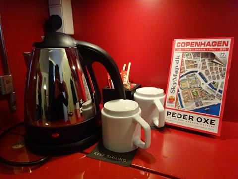 Chrome kettle, two white mugs and Copenhagen map on the red table
