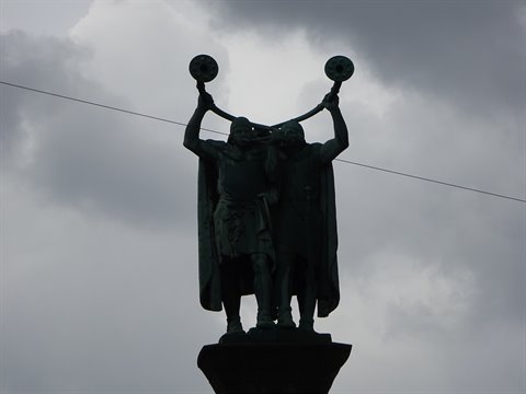 Bronze statue of the Lur players in Copenhagen, two figures raising ceremonial horns against cloudy sky