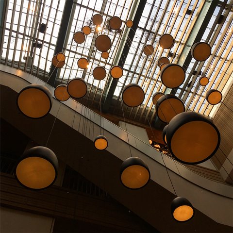 Round pendant lamps hanging under the glass roof of a modern atrium