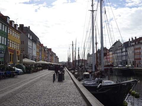 Nyhavn in Copenhagen: wooden boats moored along the canal, colorful townhouses and cobblestone promenade