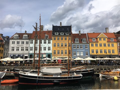 Sailboats moored at Nyhavn, Copenhagen, in front of colorful townhouses under clouds