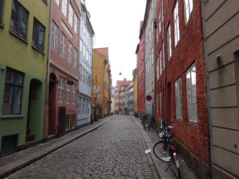Cobbled alley with colorful houses and bicycles leaning against brick walls