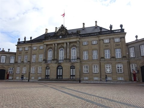 Baroque facade of Amalienborg in Copenhagen, cobbled square with Danish flag
