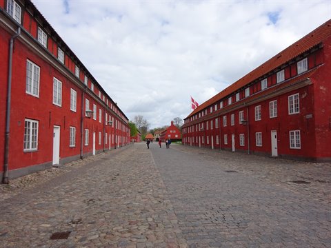 Red brick barracks and cobbled lane at Kastellet, Copenhagen, under cloudy sky