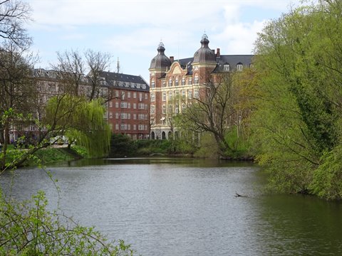 Brick building with towers overlooks the lake among willows in Copenhagen