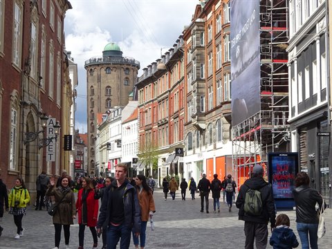 Pedestrians on a Copenhagen shopping street with the Round Tower behind