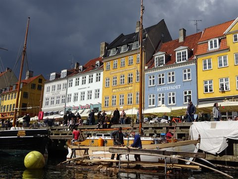 Colorful Nyhavn houses in Copenhagen, wooden boats and tourists along the quay