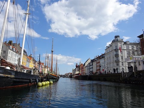Nyhavn, Copenhagen: moored sailing ships among colorful houses under white clouds
