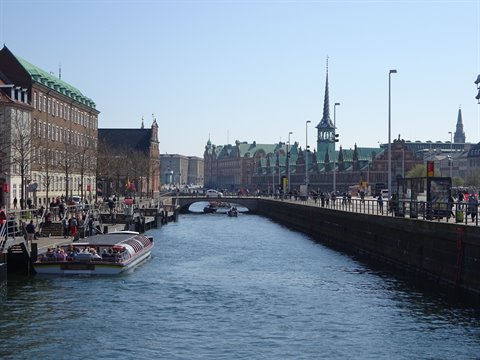 Tour boat on Copenhagen canal, the stock exchange with twisted spire behind