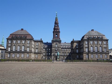 Christiansborg Palace in Copenhagen, dark stone facade with central tower and empty square