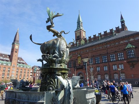 Bronze dragon fountain in front of Copenhagen City Hall, tourists and bicycles