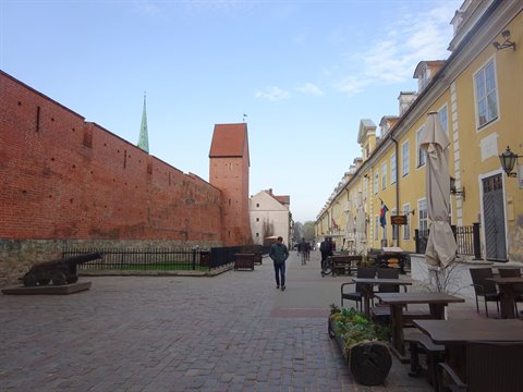 Red brick walls and medieval tower along cobblestone street in Riga