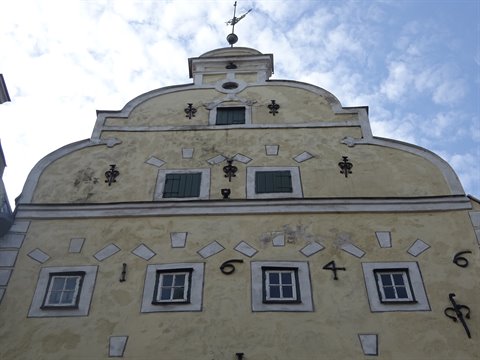Yellow facade with curved gable, date 1646 and green shutters