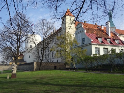 Riga Castle white tower and red roofs among bare trees