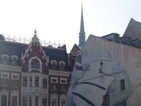 Mural on plastered wall beside Riga Art Nouveau building, morning light