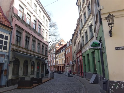 Cobblestone street with colorful buildings and lantern in Riga