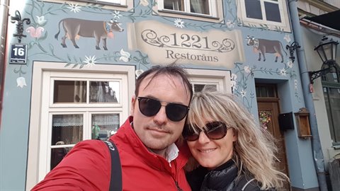 Couple taking selfie in front of the painted 1221 Restorāns facade in Riga
