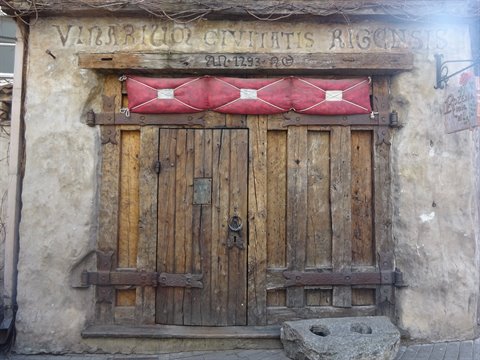 Old wooden winery door with red bundles and painted inscription above