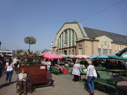 Riga Central Market, visitors among green stalls and colorful umbrellas