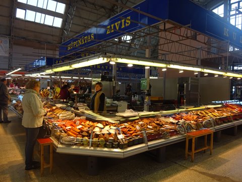 Fish stalls inside Riga's covered market hall, daylight through large windows