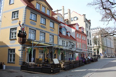 Café among colorful old-town buildings, outdoor tables on cobblestone street