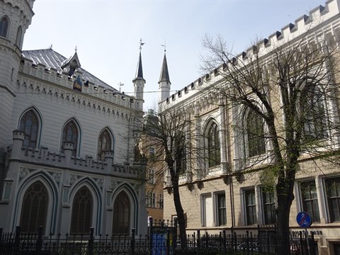 Neo-Gothic facades with pointed arches and small towers among bare trees, Riga