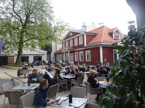 Café terrace with wicker tables before a red wooden house
