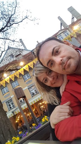 Couple selfie at Tallinn's Raekoja Plats square with yellow banners