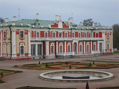 Red and white baroque palace with formal garden and circular fountain at Kadriorg