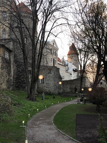 Tallinn medieval stone walls and towers among bare trees along a lit path