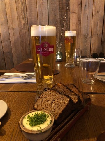 A. Le Coq beer with rye bread and chive butter on wooden table