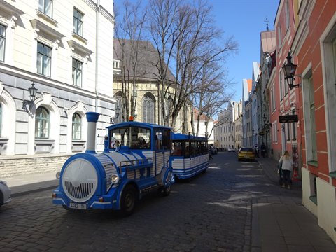 Blue tourist trackless train on cobblestone street in Tallinn old town