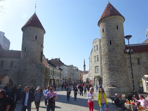 Tourists walk beneath the medieval stone towers of Tallinn's Viru Gate