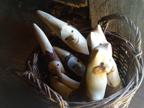 Carved wooden animal figurines resting in a wicker basket