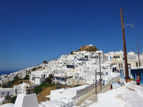 Whitewashed cubic houses of Chora village, Ios, under blue sky