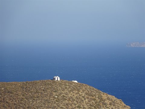 White chapel alone on dry hill above deep blue sea