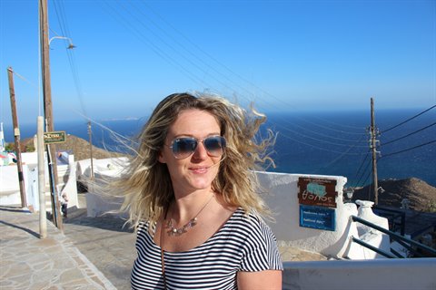 Woman in sunglasses on white stone steps with lime-washed walls and sea