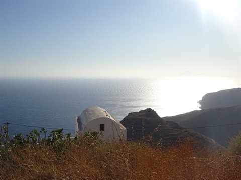 Small white chapel with vaulted roof on the cliff, sparkling sea