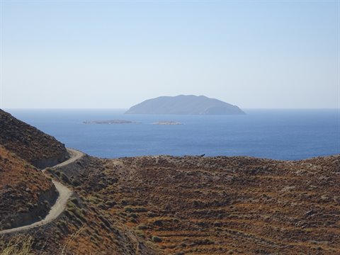 dirt road across arid hills toward an island on the blue sea