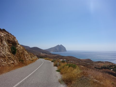 Asphalt coastal road with Mediterranean scrub and rocky headland over the sea