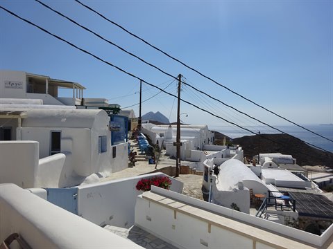 Whitewashed Cycladic village with lime houses above the blue sea