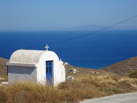 White chapel with blue door and cross by the Aegean sea