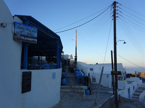White and blue taverna by a cobbled stairway, Cycladic houses at dusk