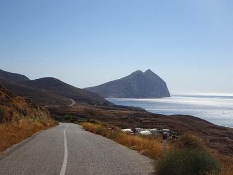 Asphalt road toward the sea, dry hills and a rocky islet ahead, Kalymnos