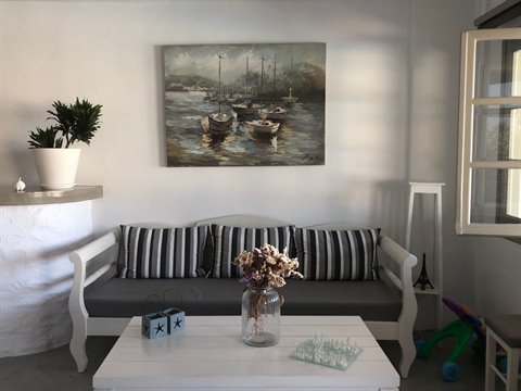 White sofa with striped cushions, boat painting, glass vase with dried flowers