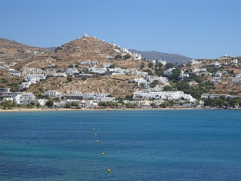 White houses on the hill above the beach, blue sea with floating buoys