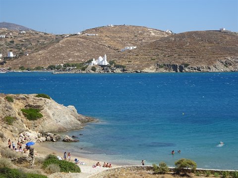 Turquoise bay with swimmers on the beach and a white church on the hills