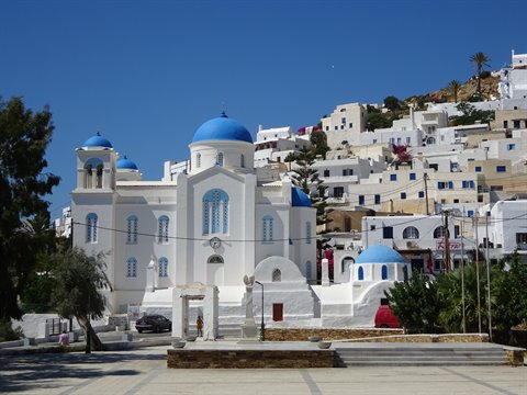 White church with blue domes and whitewashed houses in Ios