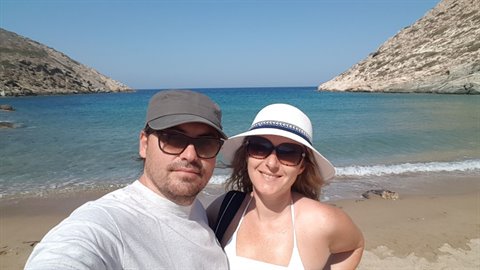 Couple in sunglasses and hats taking a selfie on the beach