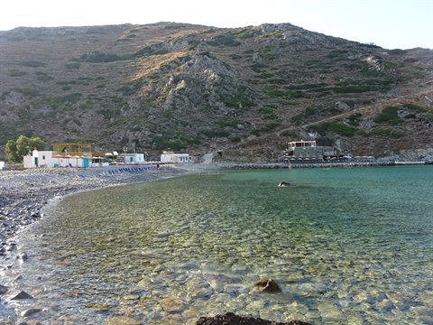 Pebbly beach with crystal-clear water and arid hills in Sifnos